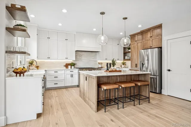 a kitchen with stainless steel appliances kitchen island granite countertop a table chairs refrigerator and microwave