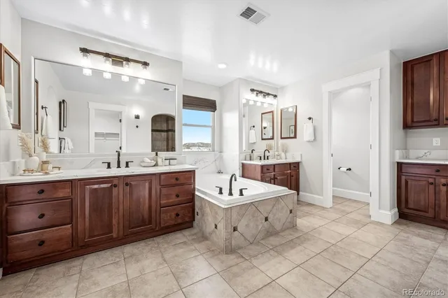 a spacious bathroom with a double vanity sink mirror and bathtub