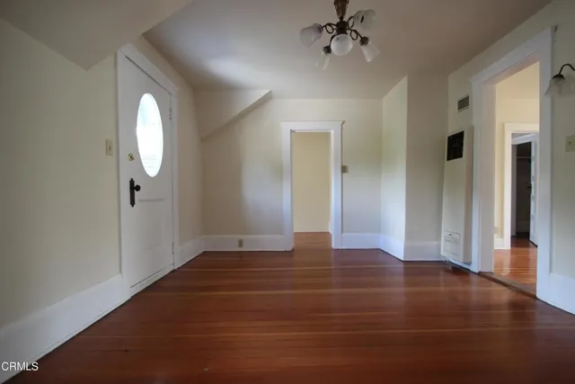 a view of an empty room with wooden floor and a window