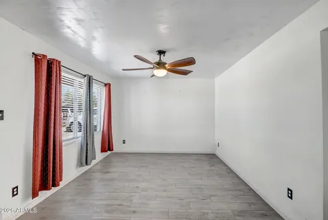 an empty room with ceiling fan and windows