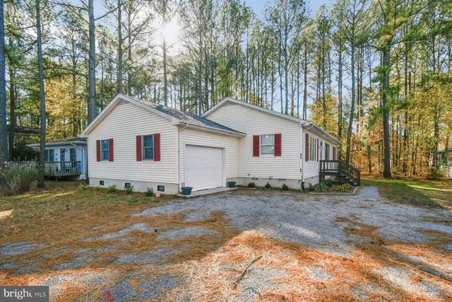 a view of a white house next to a yard with a large tree