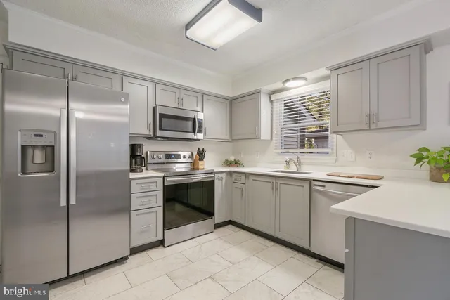 a kitchen with granite countertop a sink stainless steel appliances and window
