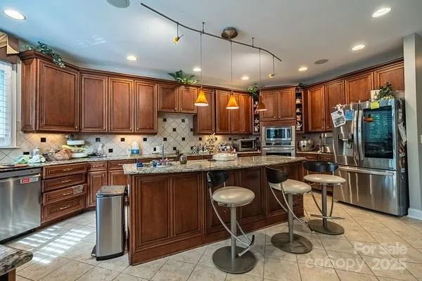 a kitchen with stainless steel appliances granite countertop sink stove refrigerator and cabinets
