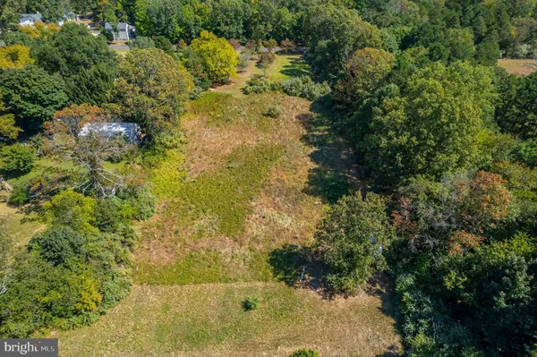 an aerial view of residential houses with outdoor space and trees all around