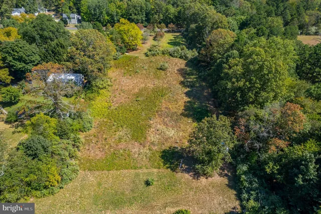 an aerial view of residential houses with outdoor space and trees all around