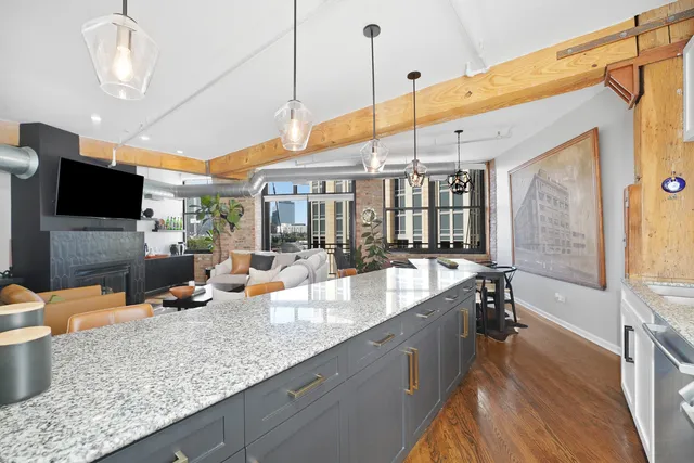 a large kitchen with a large counter top a sink a counter space and stainless steel appliances