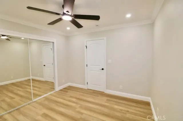 an empty room with wooden floor and a ceiling fan