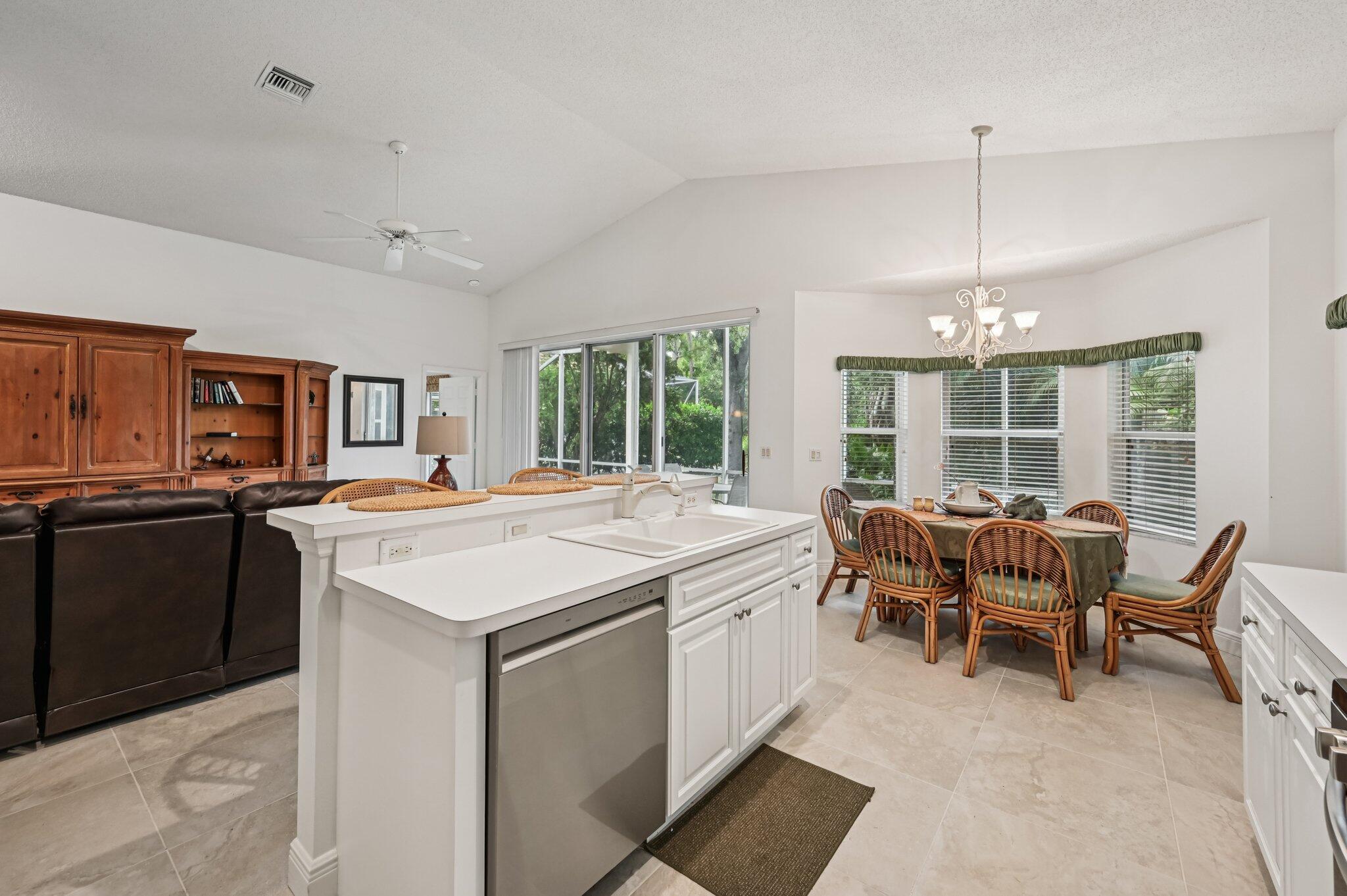 7184 Southeast Magellan Lane Stuart, FL 34997 - Photo 14 of 34 a open kitchen with stainless steel appliances granite countertop a stove top oven a sink dishwasher a dining table and chairs with wooden floor