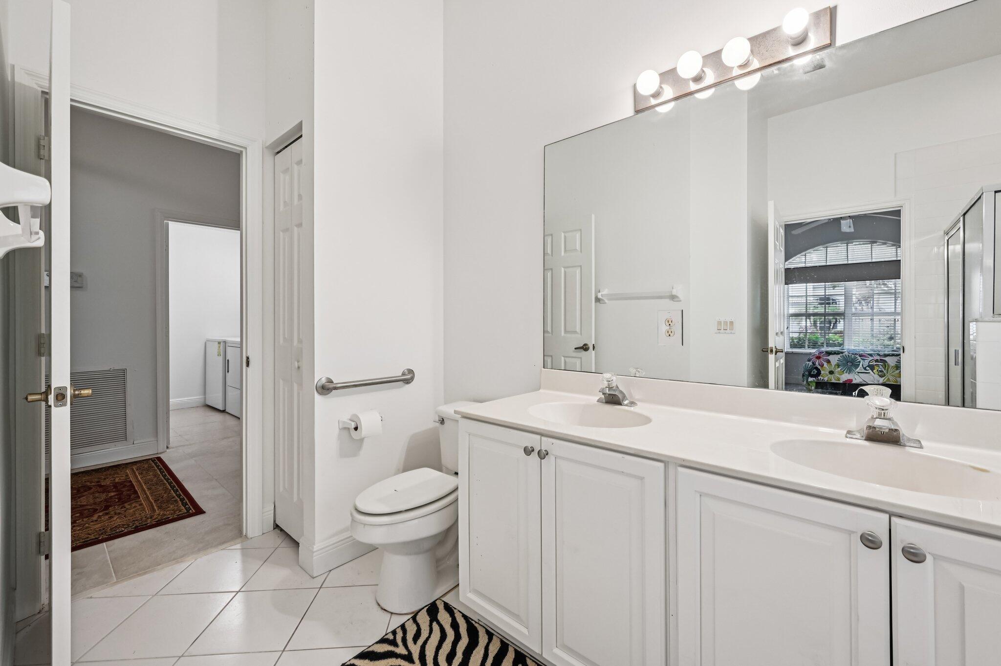 7184 Southeast Magellan Lane Stuart, FL 34997 - Photo 19 of 34 a bathroom with a sink a toilet a large mirror and shower