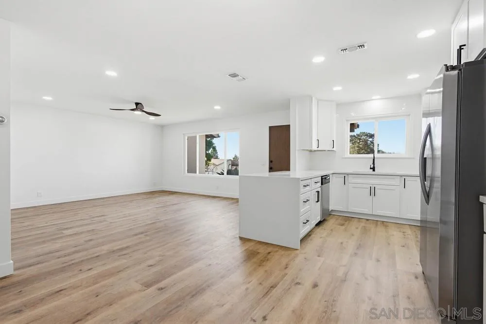 4379 Albatross Way Oceanside, CA 92057 - Photo 11 of 44 a large kitchen with a wooden floor and white stainless steel appliances