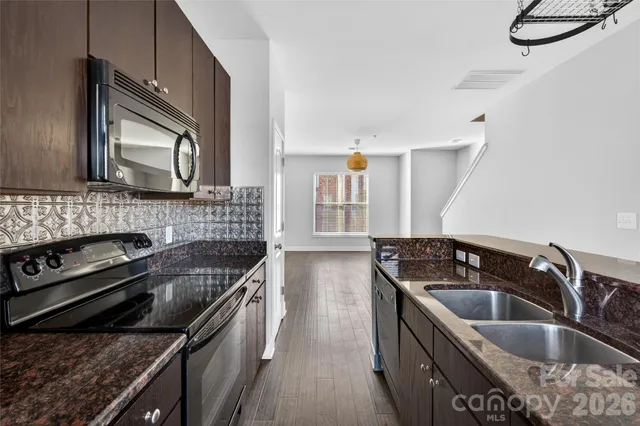a kitchen that has a sink wooden cabinets and stainless steel appliances
