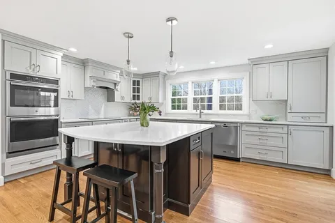 a kitchen with granite countertop a stove a sink dishwasher a dining table and chairs with wooden floor