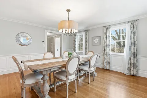 a dining room with wooden floor a chandelier a wooden table and chairs