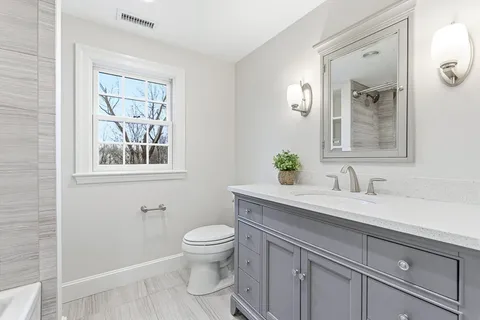 a bathroom with a granite countertop toilet sink and mirror