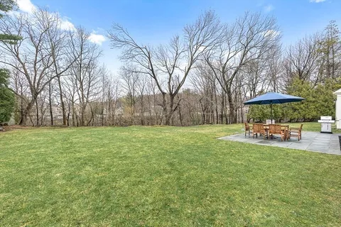 a view of a yard with table and chairs under an umbrella