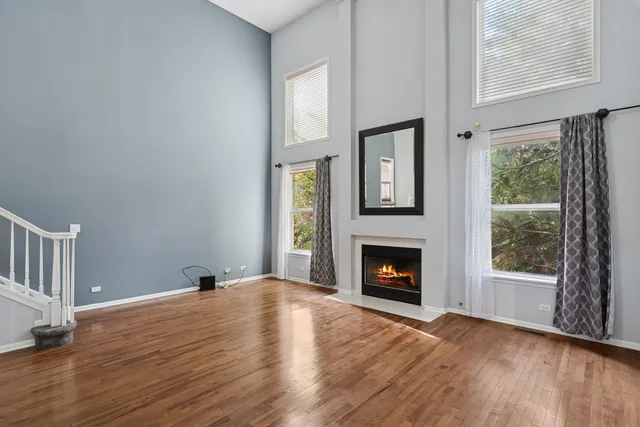 a view of an empty room with wooden floor fireplace and a window