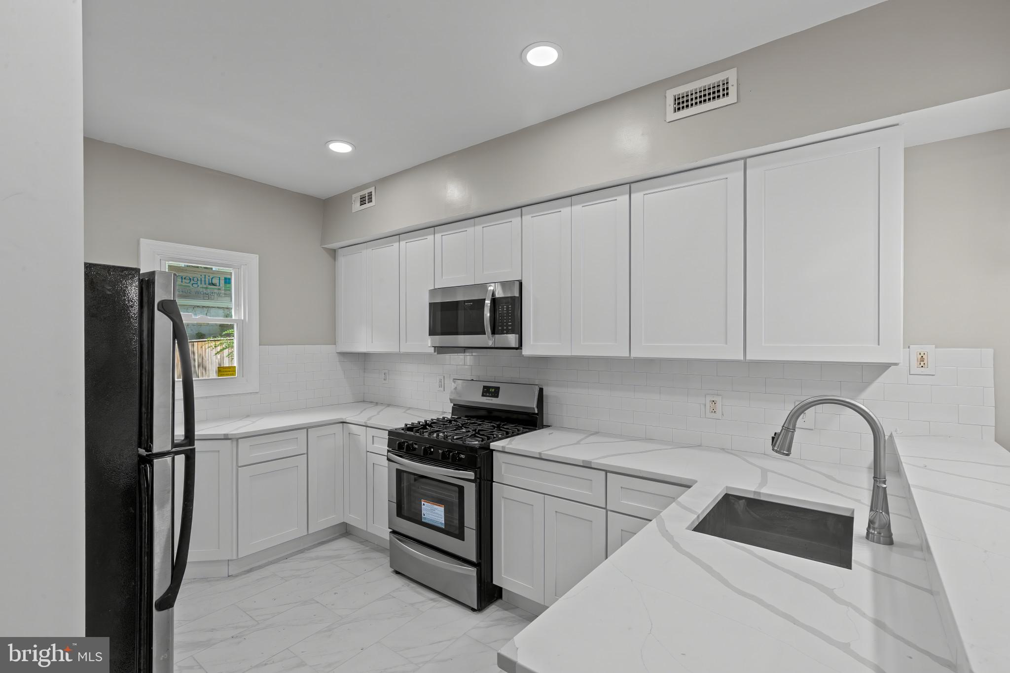 1525 West Pratt Street Baltimore, MD 21223 - Photo 11 of 40 a kitchen with stainless steel appliances a refrigerator sink and white cabinets