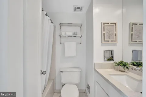 a bathroom with a granite countertop sink a toilet and a mirror