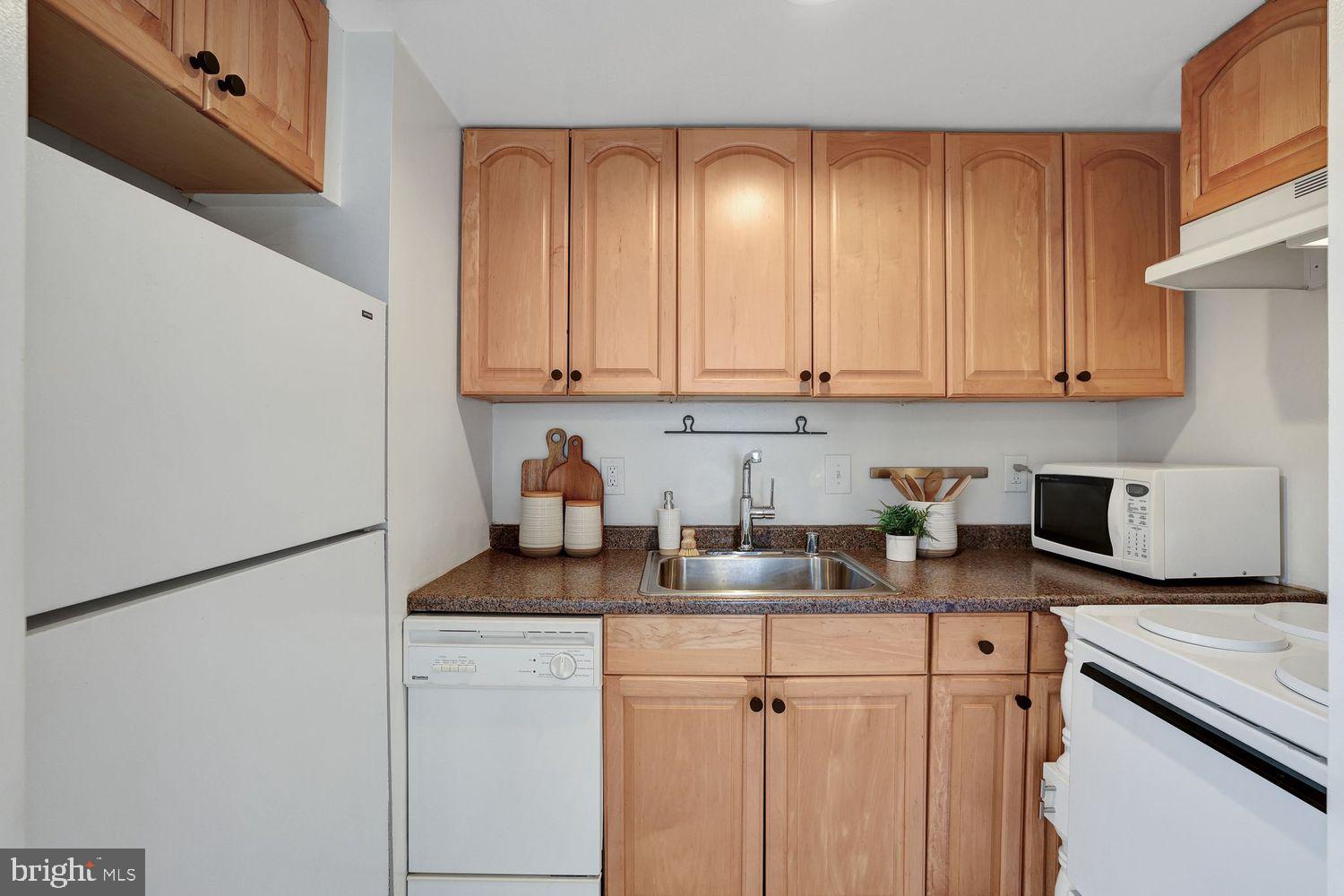 1133 13th Street Northwest, Unit 704 Washington, DC 20005 - Photo 9 of 23 a kitchen with stainless steel appliances granite countertop white cabinets sink and a granite counter top