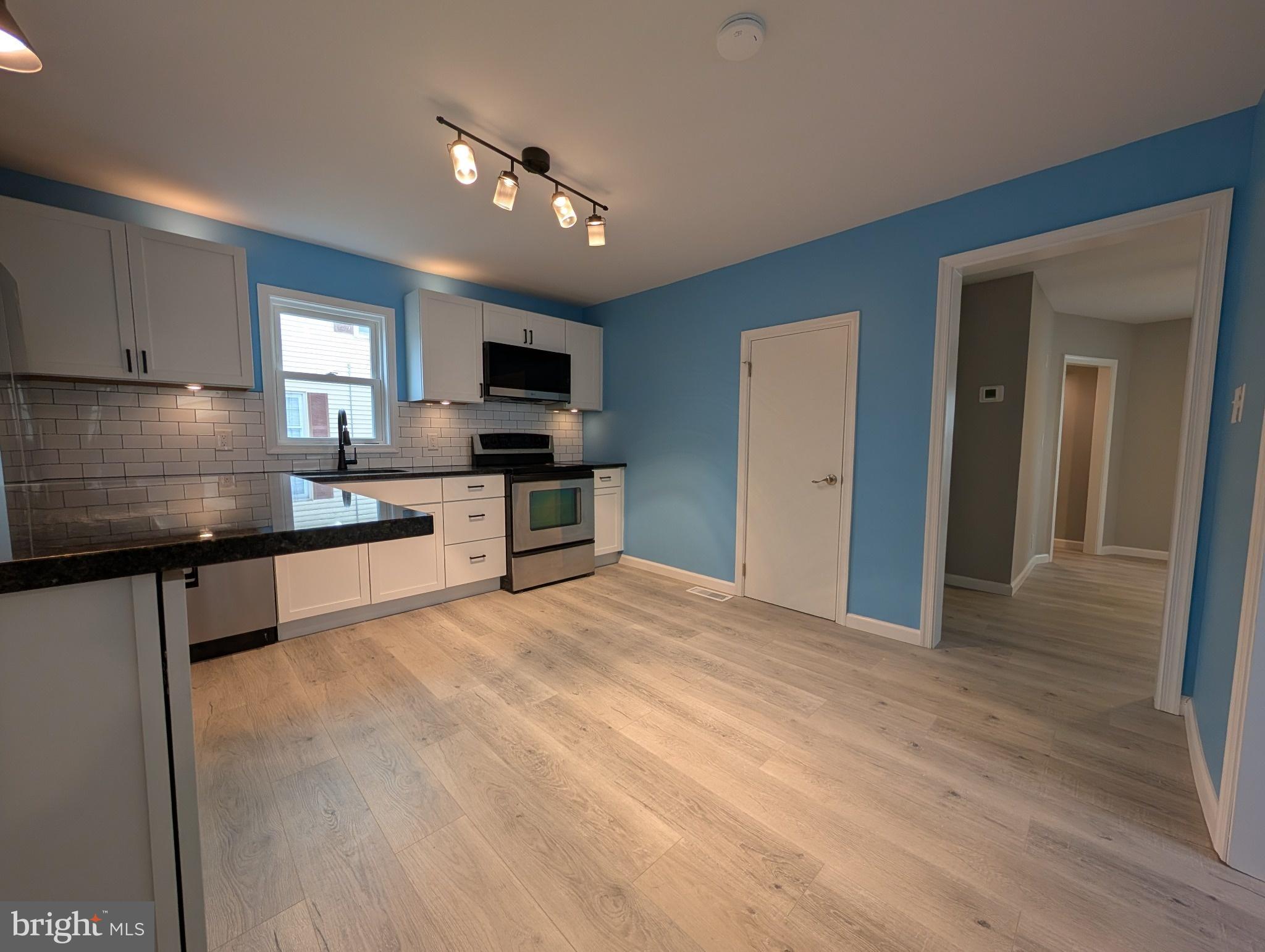 703 Madison Street Salisbury, MD 21804 - Photo 9 of 22 a large kitchen with kitchen island granite countertop a stove top oven a sink a counter space and cabinets