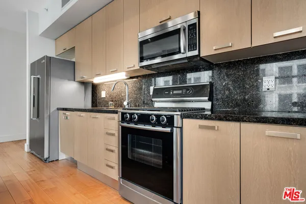 a kitchen with stainless steel appliances granite countertop a stove microwave and refrigerator