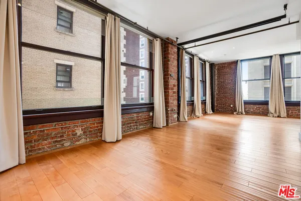 a view of a hallway with wooden floor and a kitchen