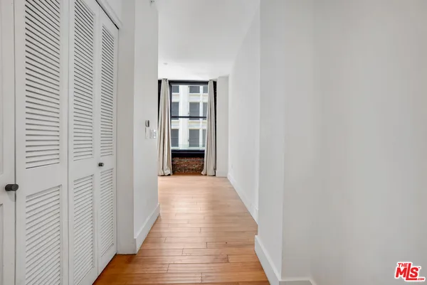 a view of a hallway with wooden floor and closet