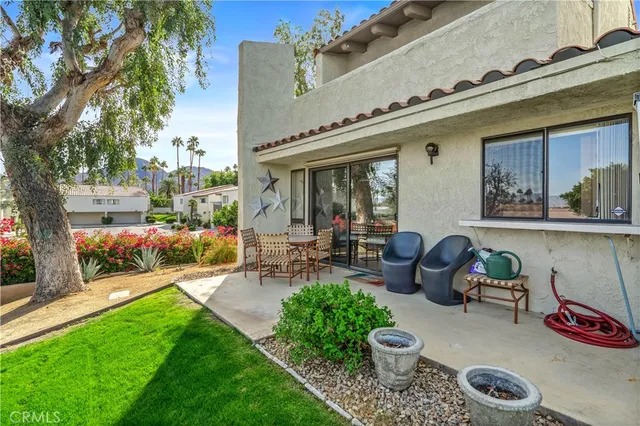 a view of a patio with table and chairs potted plants and a large tree