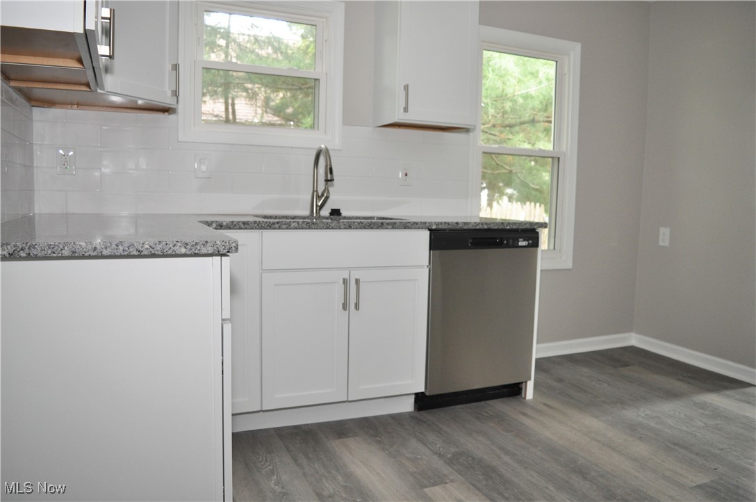 7604 Spafford Road Cleveland, OH 44105 - Photo 17 of 23 Kitchen featuring dishwasher, a sink, dark wood-type flooring, backsplash, and stone countertops