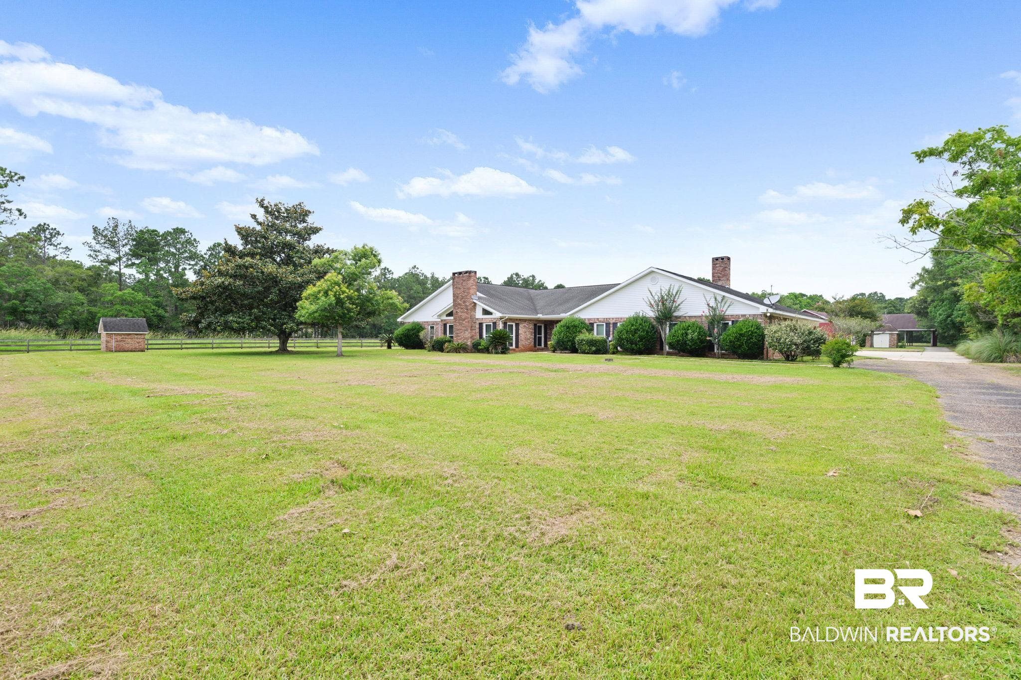 7540 2 Mile Road Irvington, AL 36544 - Photo 73 of 82 Expansive green lawn surrounds a single-story residence with a white exterior, brick accents, and two brick chimneys