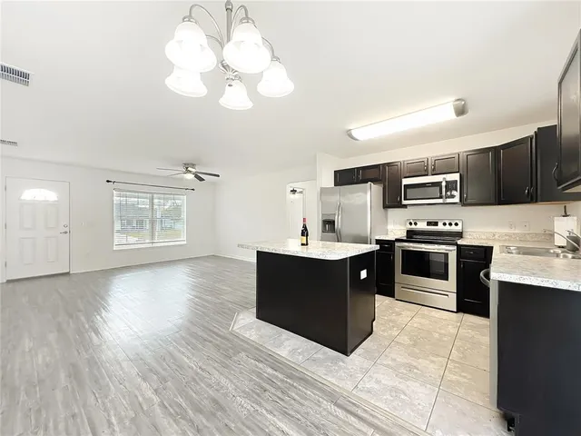 a large kitchen with stainless steel appliances granite countertop a stove a sink dishwasher and a microwave oven with wooden floor