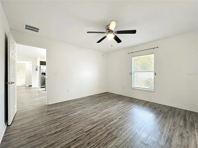 a view of empty room with wooden floor and fan