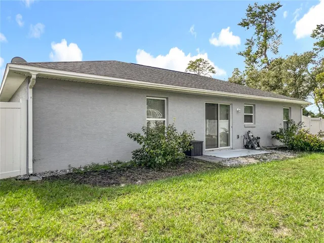 a backyard of a house with table and chairs plants and large tree