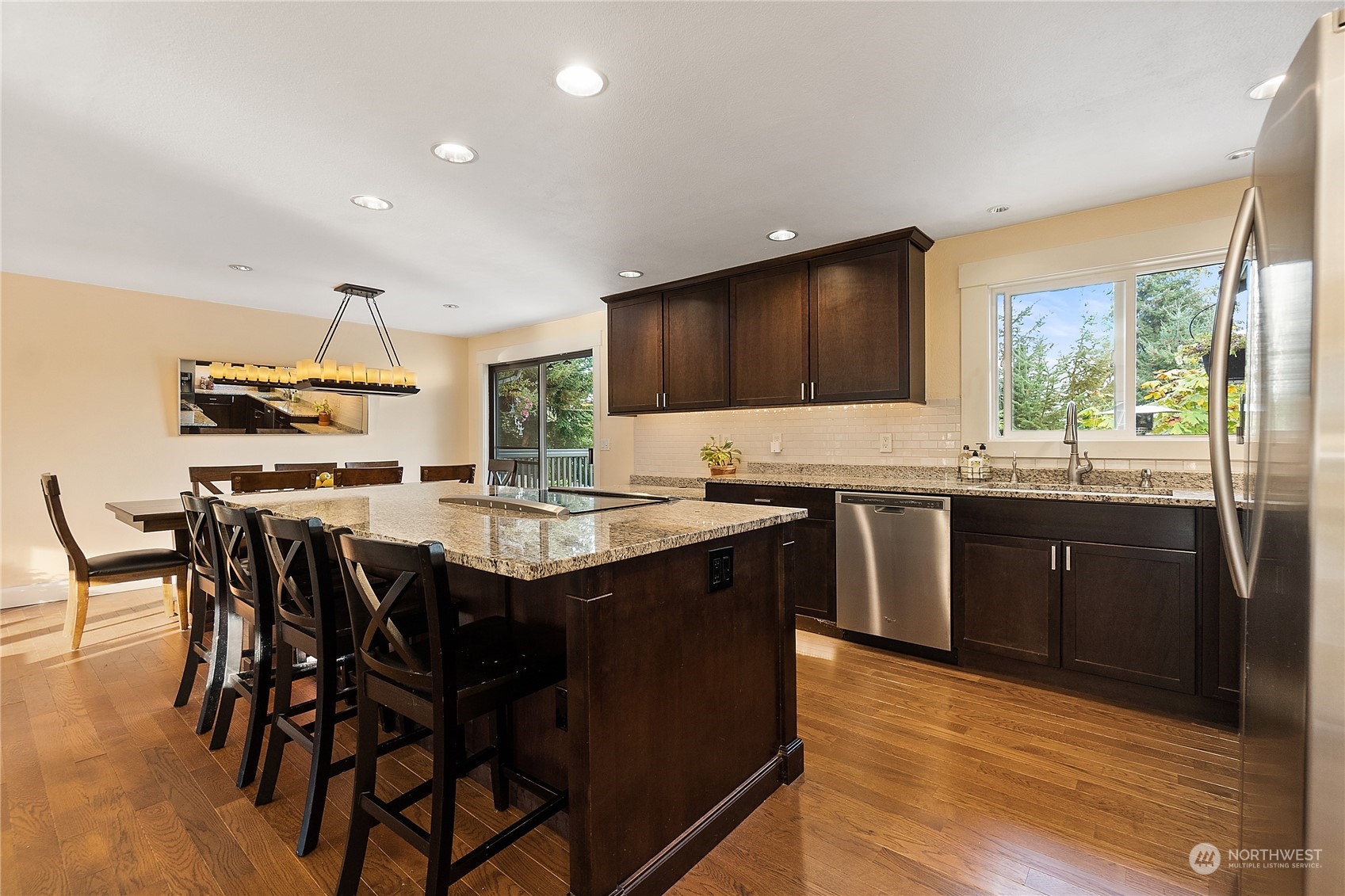 18434 129th Lane Northeast Bothell, WA 98011 - Photo 6 of 33 a kitchen with stainless steel appliances granite countertop wooden cabinets a stove top oven a sink with dining table and chairs