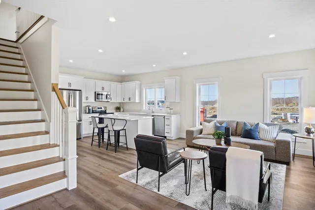a living room with lots of furniture and kitchen view with wooden floor