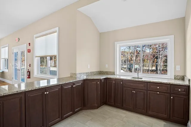 a large kitchen with granite countertop a sink and dishwasher wooden cabinets with a large window
