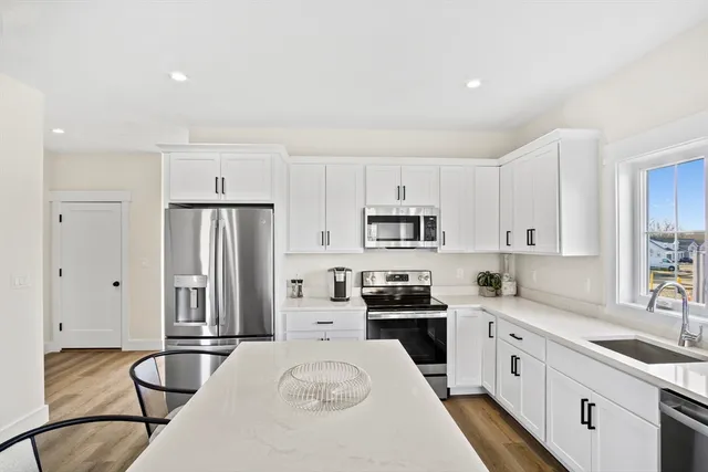 a kitchen with stainless steel appliances granite countertop a sink refrigerator stove and microwave