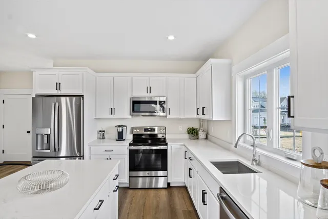 a kitchen with stainless steel appliances granite countertop a sink stove refrigerator and cabinets