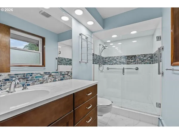 a bathroom with a sink a toilet a mirror and shower