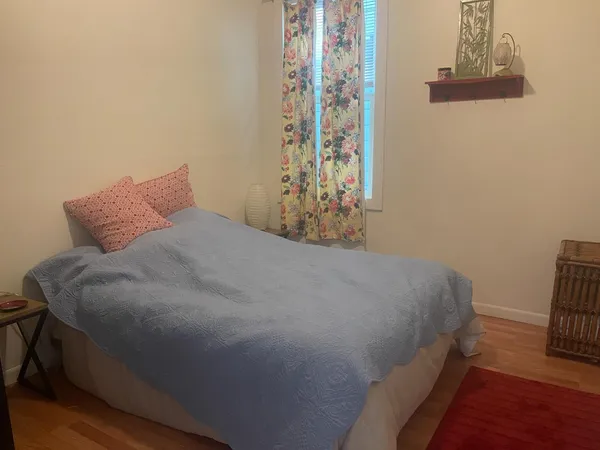 a bed sitting in a bedroom next to a window and a chandelier