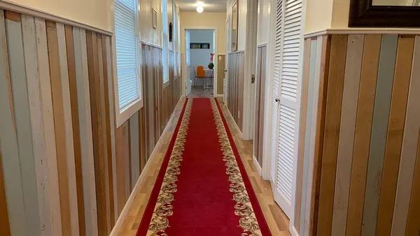 a view of a hallway with wooden floor and stairs
