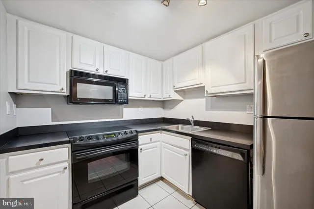 a kitchen with white cabinets and refrigerator
