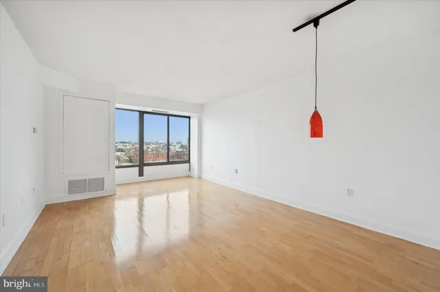 a view of an empty room with a window and kitchen view