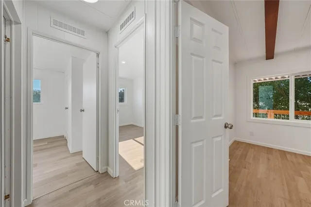 a view of an empty room with a window and wooden floor