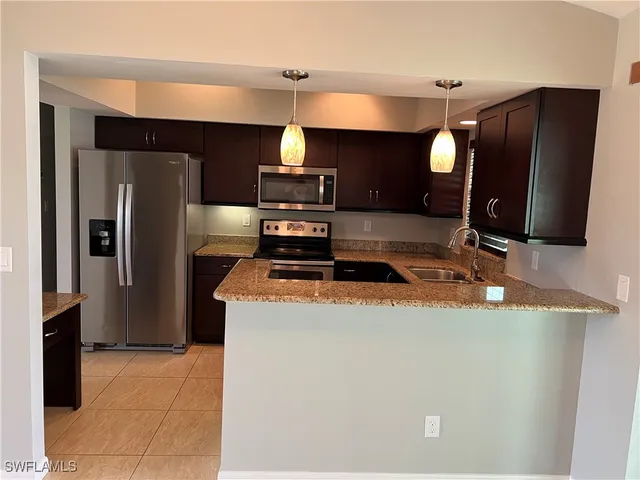 a kitchen with stainless steel appliances granite countertop a refrigerator a stove and a sink