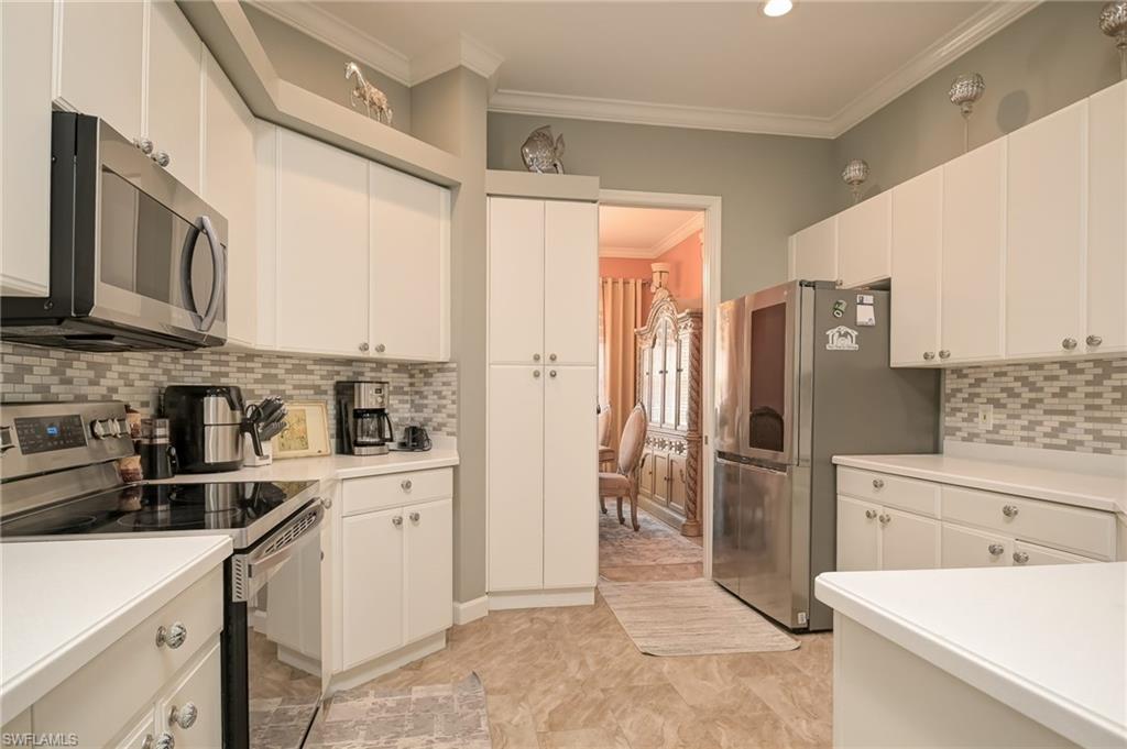 3144 Sundance Circle Naples, FL 34109 - Photo 13 of 26 Kitchen with stainless steel appliances, crown molding, backsplash, light countertops, and white cabinets