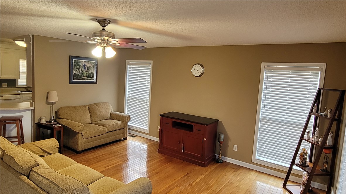 325 McAdams School Road Honea Path, SC 29654 - Photo 11 of 22 Hardwood flooring extends throughout this well-lit living area, featuring multiple windows and an open view to the kitchen.