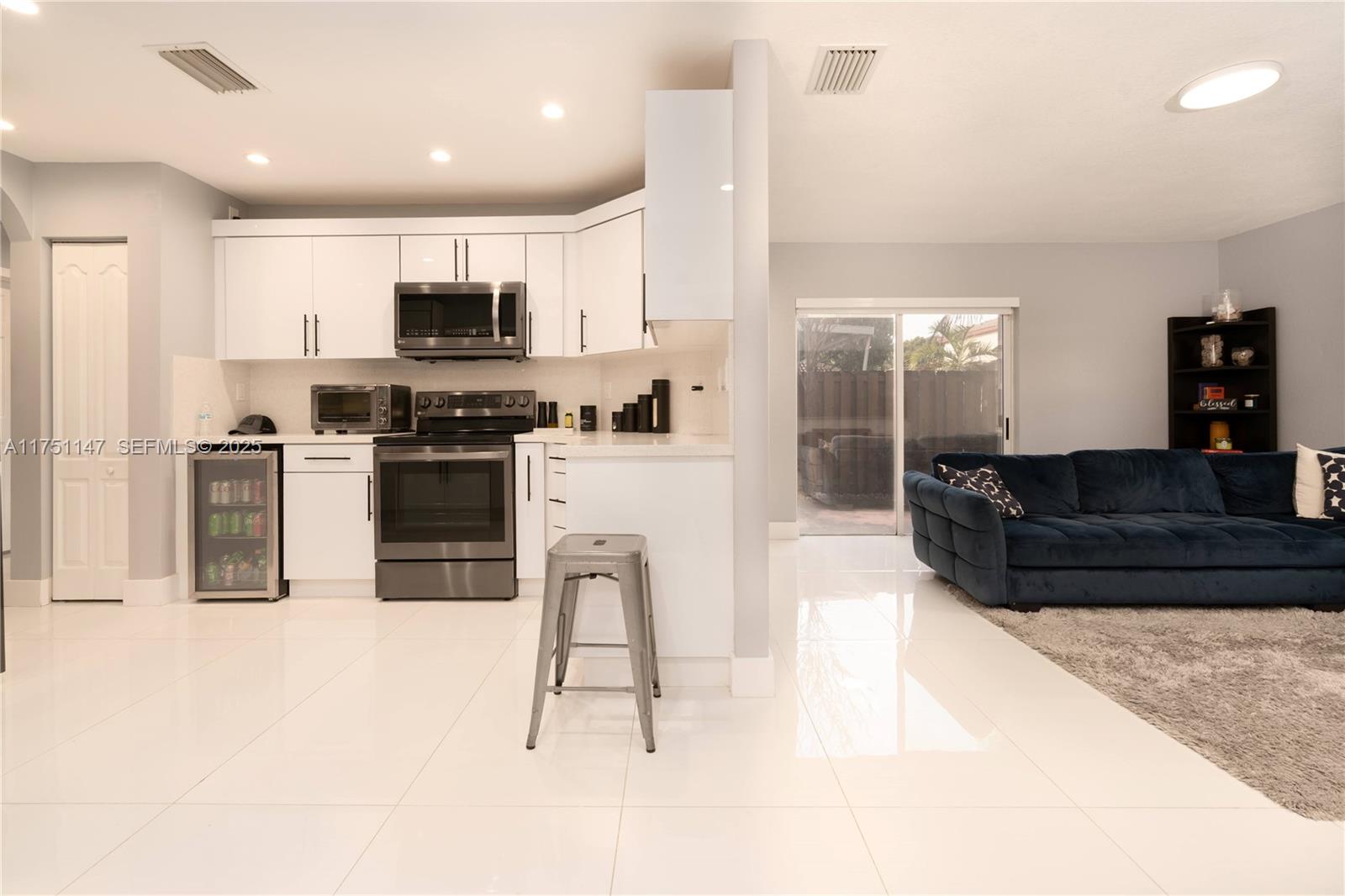 19444 Northwest 79th Court Hialeah, FL 33015 - Photo 12 of 26 a kitchen with stainless steel appliances kitchen island granite countertop a stove top oven a sink a dining table and chairs with wooden floor