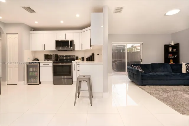 a kitchen with stainless steel appliances kitchen island granite countertop a stove top oven a sink a dining table and chairs with wooden floor