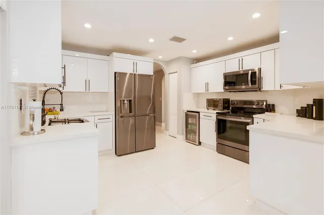 a kitchen with kitchen island a refrigerator and a sink